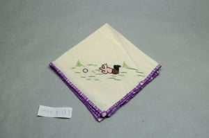 Image of Figure lying on ground with ball in front of them, one of a set of 3 embroidered napkins, each with single Inuit figure